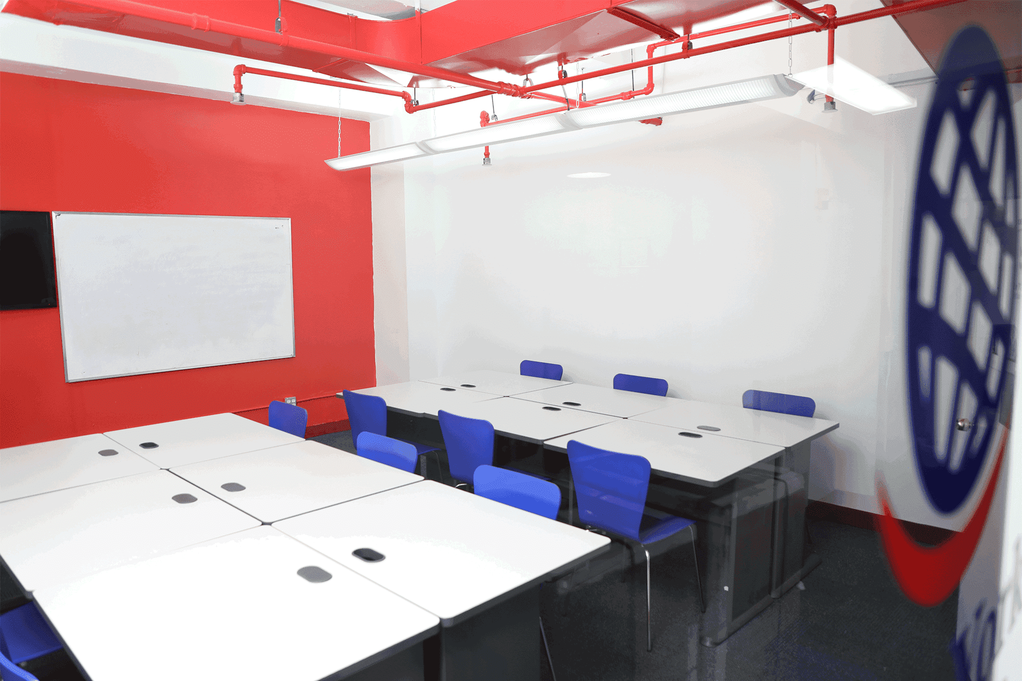 Conference room with white tables and blue chairs at New York English Center.