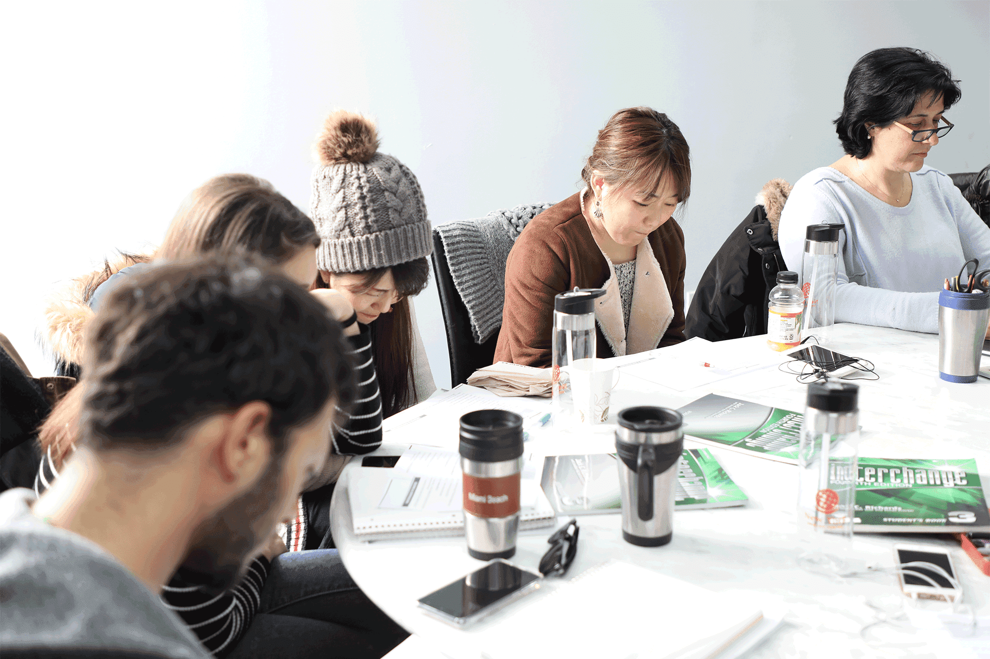 Image of students studying at New York English Center, gathered around a table with notebooks and coffee.