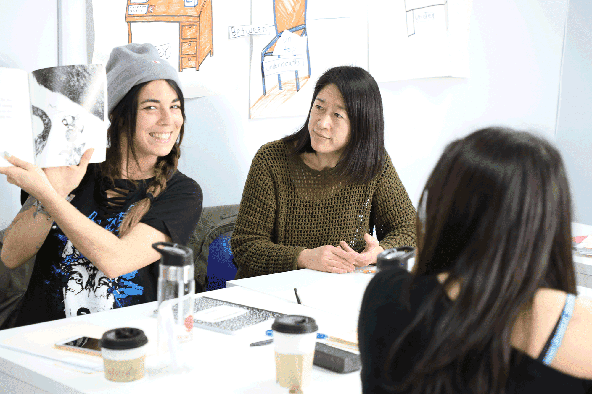 Three individuals studying at the New York English Center, seated at a table with a drawing.